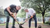 Profesor y directivo del Tec sostienen palas antes de plantar un arbol.