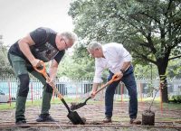 Profesor y directivo del Tec sostienen palas antes de plantar un arbol.